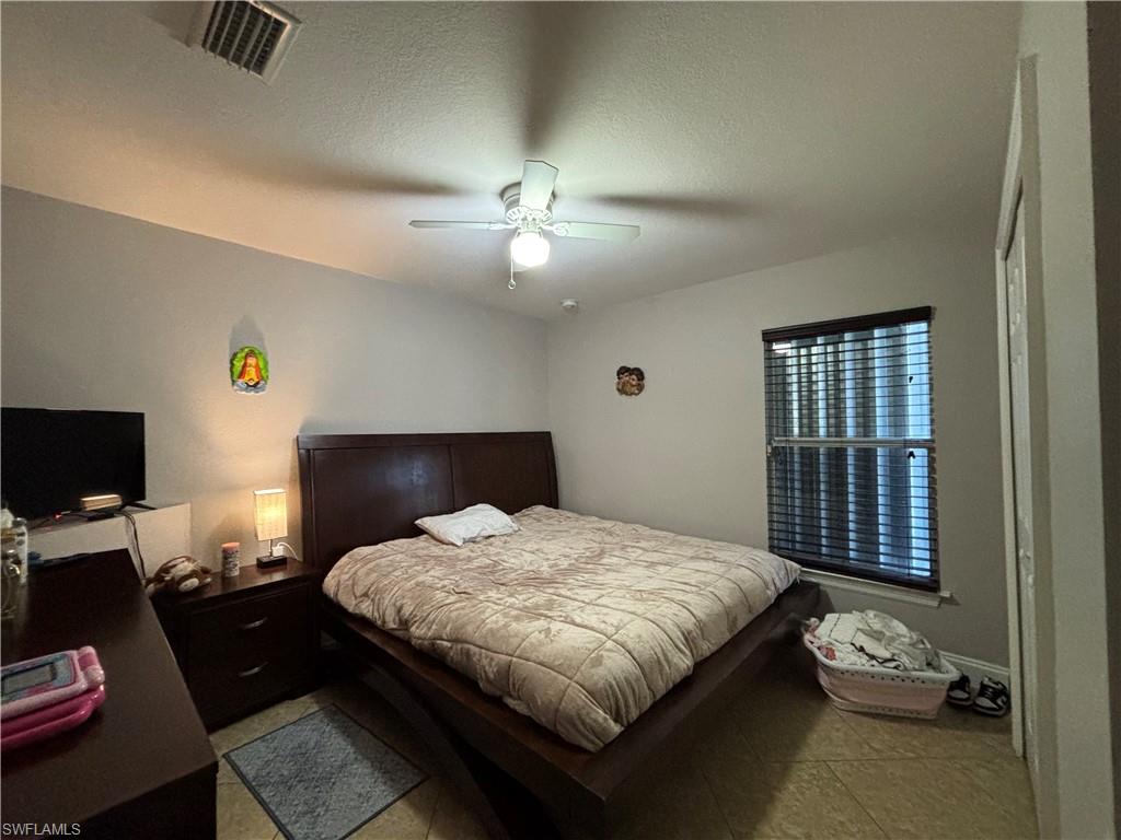 1243 Madison Court Immokalee, FL 34142 - Photo 18 of 32 a bedroom with a bed and a chandelier