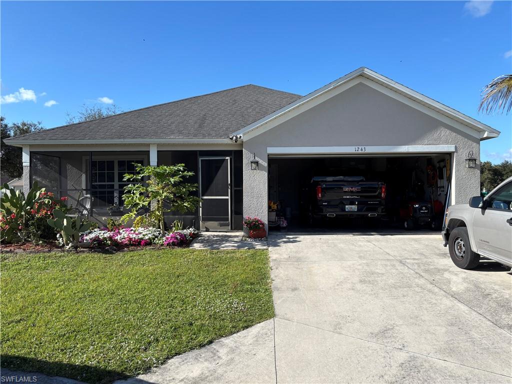 1243 Madison Court Immokalee, FL 34142 - Photo 2 of 32 a front view of a house with a yard and garage