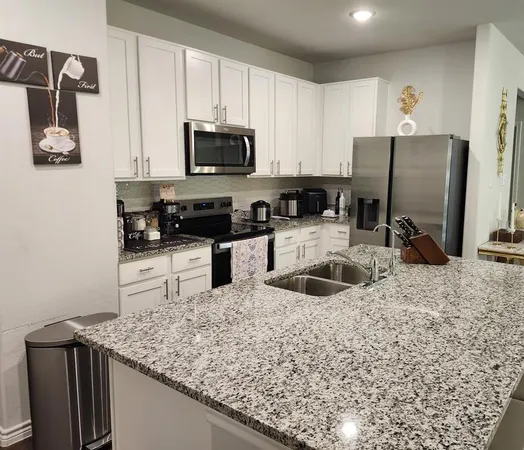 a kitchen with stainless steel appliances granite countertop a sink a stove and refrigerator