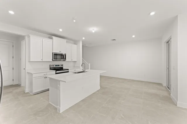 a kitchen with stainless steel appliances a white stove top oven a sink a refrigerator and white cabinets