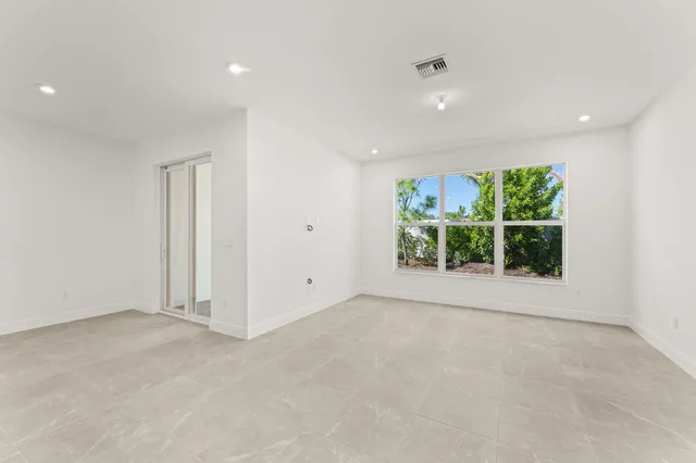 a view of an empty room with a window and kitchen view