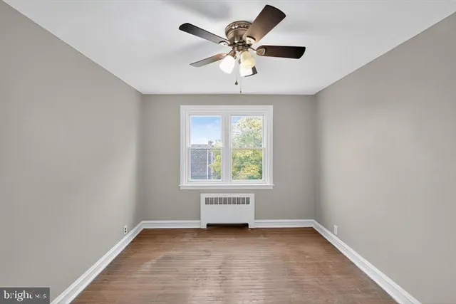 an empty room with a window and a fan