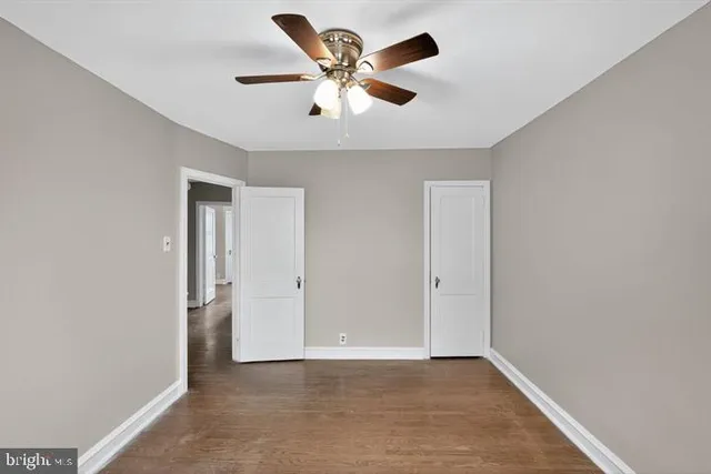 an empty room with chandelier fan and windows