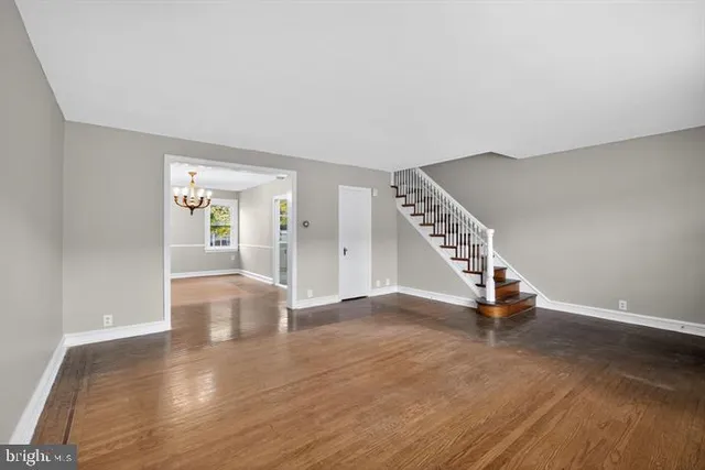 a view of an empty room with wooden floor and stairs