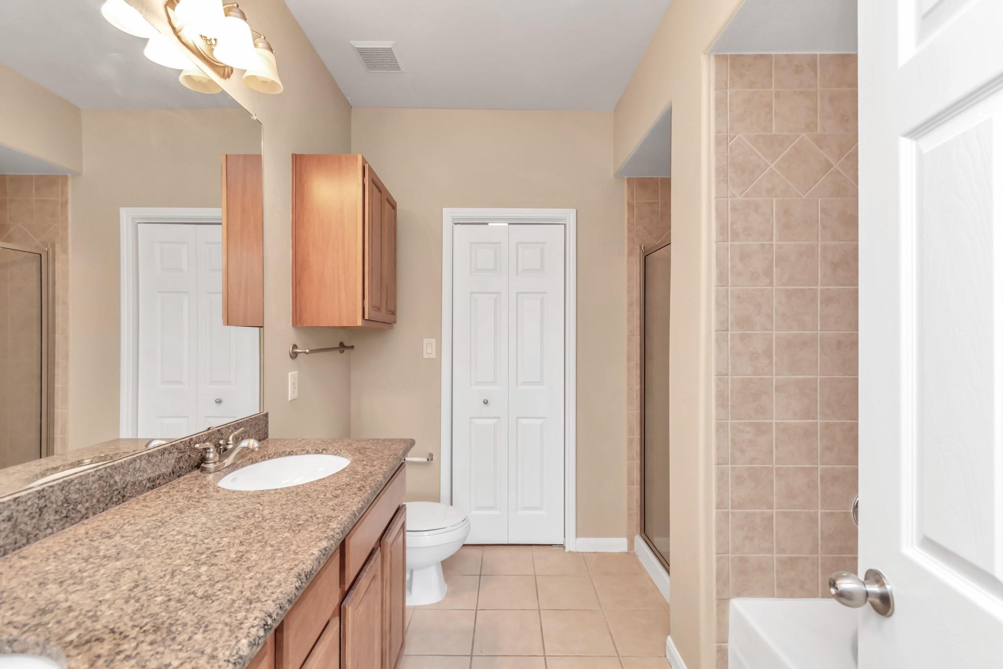 9200 Westheimer Road, Unit 1607 Houston, TX 77063 - Photo 18 of 34 a bathroom with a granite countertop sink a mirror and a shower