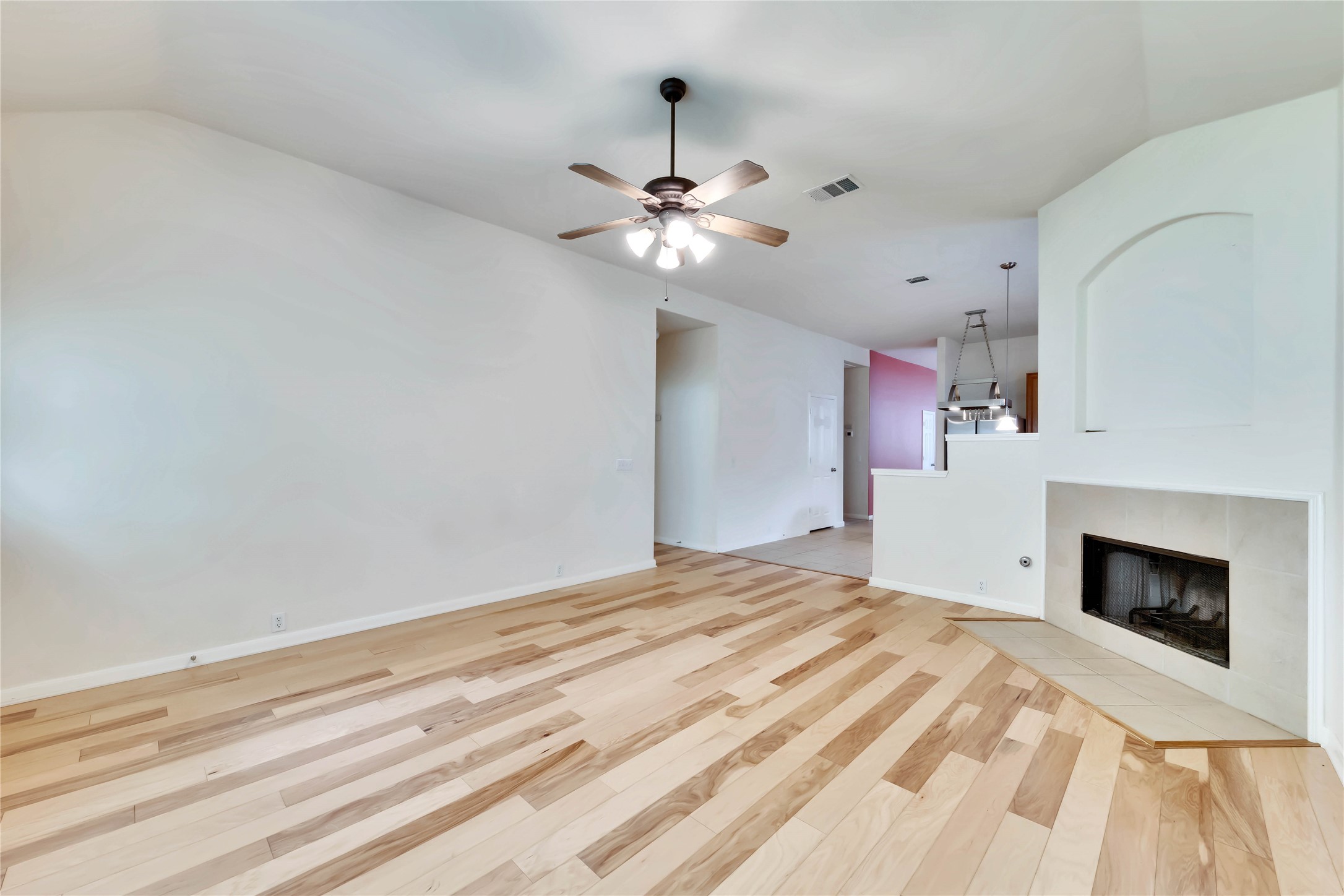 2133 Paradise Ridge Drive Round Rock, TX 78665 - Photo 15 of 22 Spacious living area featuring light wood-finish flooring, a contemporary ceiling fan, and a tiled fireplace hearth
