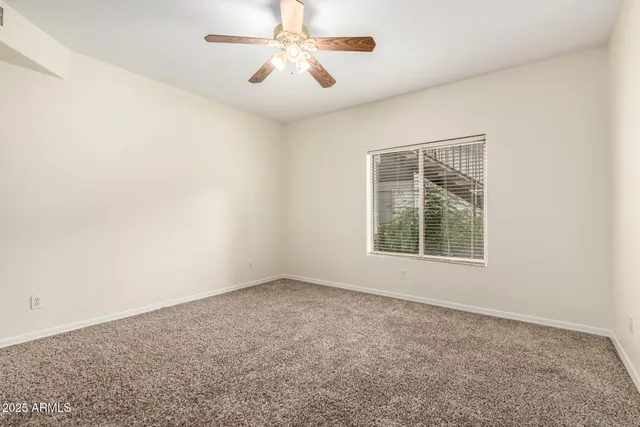 an empty room with a window and a fan