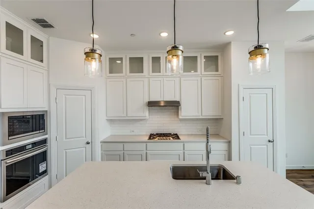 a large kitchen with stainless steel appliances granite countertop a stove a sink and a refrigerator