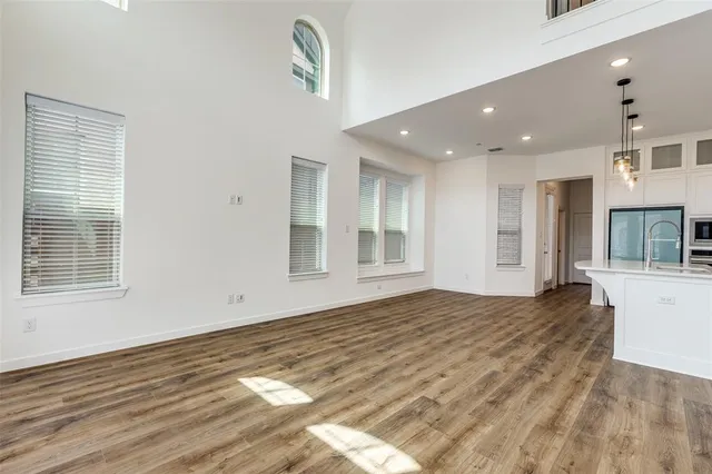 a view of an empty room with kitchen and window