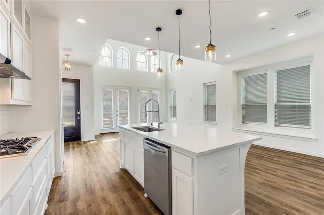 a kitchen with kitchen island a stove a sink a refrigerator and white cabinets with wooden floor