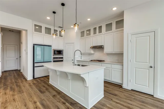 a large kitchen with kitchen island a large counter space a sink appliances and cabinets