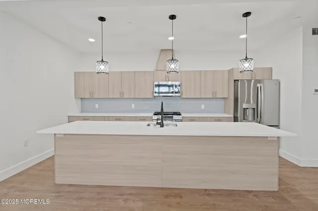 a view of a kitchen with kitchen island a center island a stove a chimney a sink and a counter top