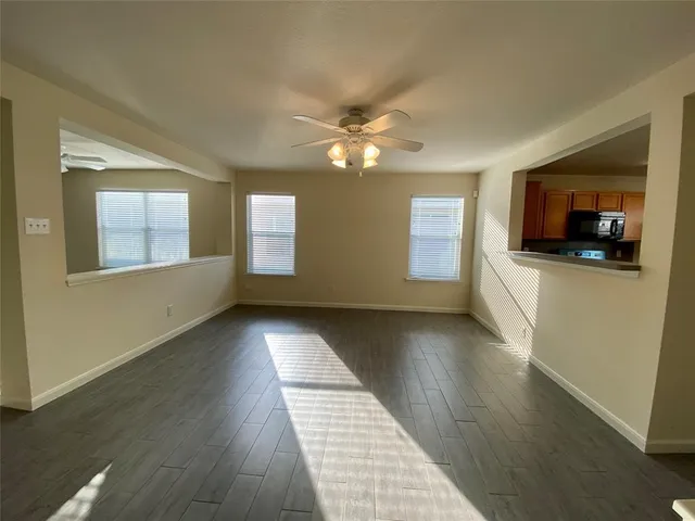 a view of an empty room with window and wooden floor