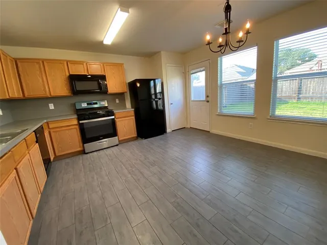 a kitchen with stainless steel appliances granite countertop a refrigerator a sink dishwasher a stove and white countertops with wooden floor