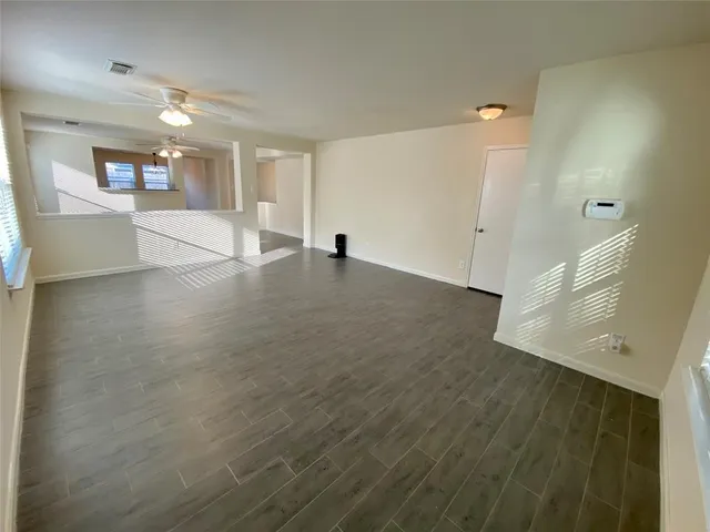 a view of a big room with wooden floor and windows