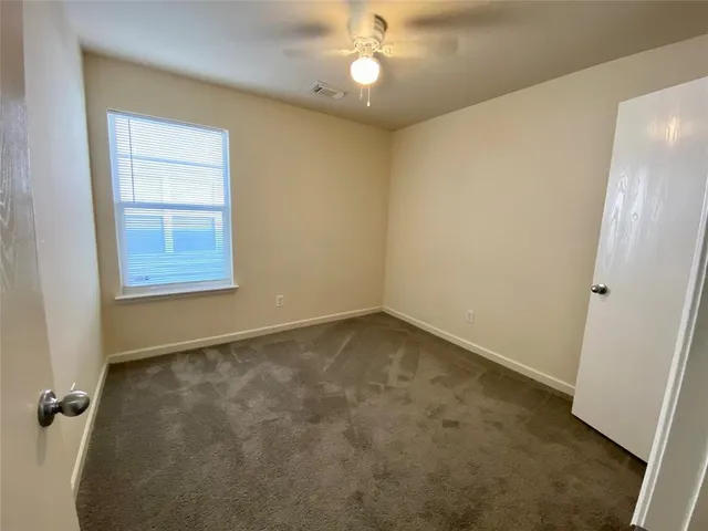 an empty room with a chandelier fan and windows