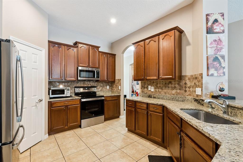 8484 Dover View Lane Orlando, FL 32829 - Photo 4 of 41 a kitchen with granite countertop a sink stainless steel appliances and cabinets