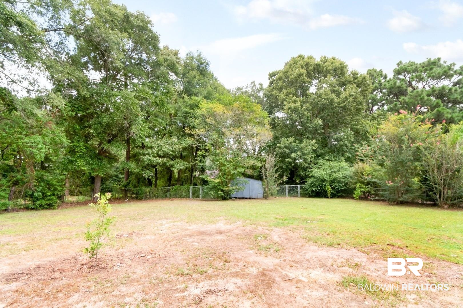 5812 Fern Valley Road Mobile, AL 36609 - Photo 32 of 32 Expansive backyard featuring a partial grass lawn, mature trees, a metal storage shed, and chain link fencing