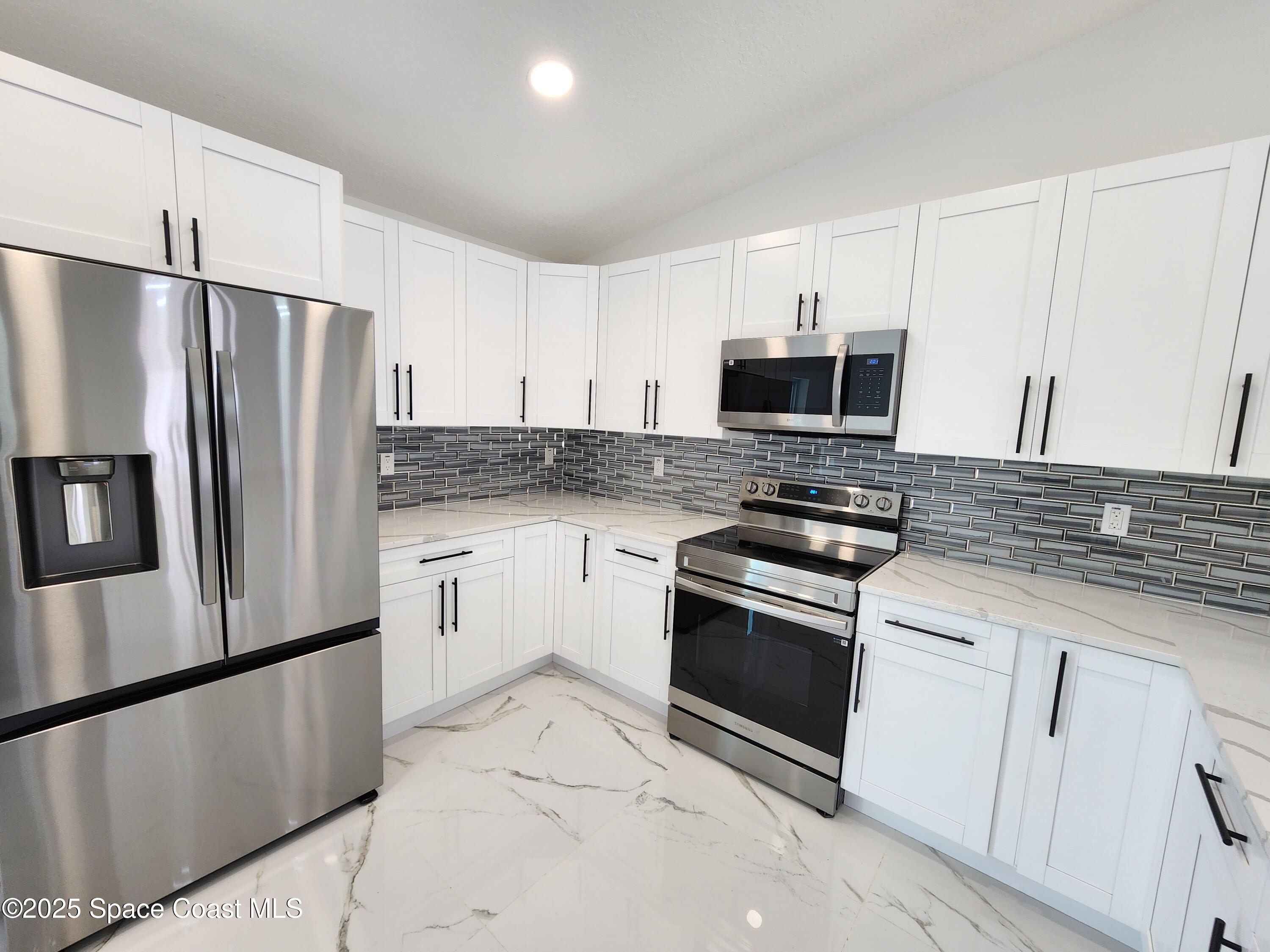 710 Bryant Road Palm Bay, FL 32908 - Photo 9 of 26 a kitchen with granite countertop a refrigerator stove and microwave