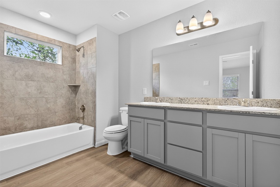 706 Universal Street Navasota, TX 77868 - Photo 19 of 40 a bathroom with a granite countertop sink a toilet a mirror and bathtub