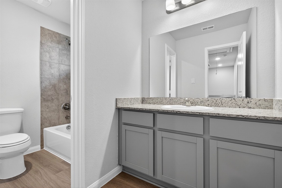 706 Universal Street Navasota, TX 77868 - Photo 23 of 40 a bathroom with a granite countertop sink a toilet and a mirror