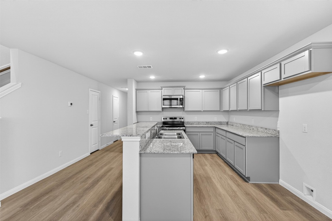 706 Universal Street Navasota, TX 77868 - Photo 8 of 40 a kitchen with stove cabinets and a wooden floor