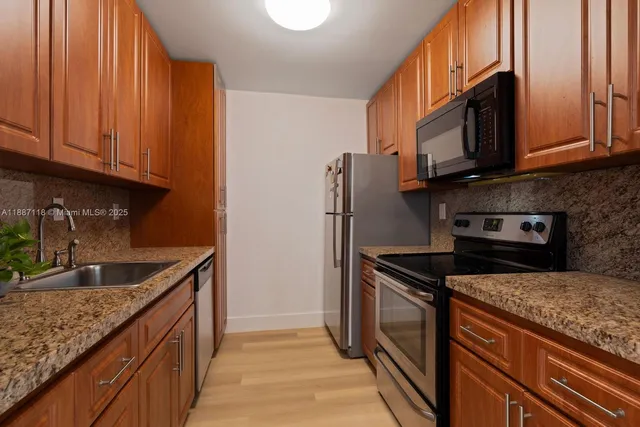 a kitchen with stainless steel appliances granite countertop a sink stove and refrigerator