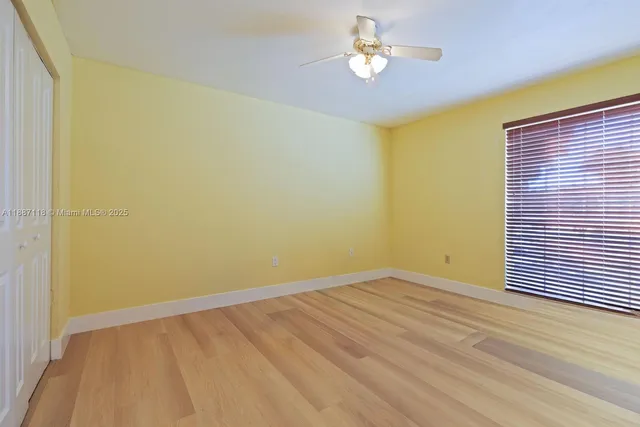 a view of empty room with wooden floor and fan