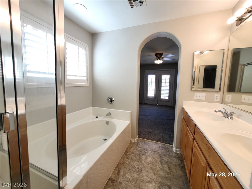9843 West Overlook Ridge Avenue Las Vegas, NV 89148 - Photo 15 of 19 Indulge in a tranquil retreat featuring a soaking tub, dual vanity, and elegant archway leading to the primary bedroom.