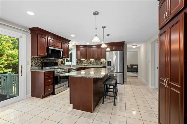 a kitchen with stainless steel appliances granite countertop a refrigerator a stove a sink a microwave and chairs