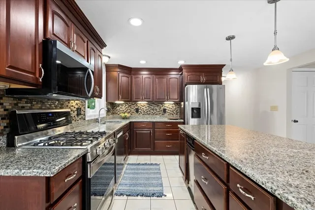 a kitchen with stainless steel appliances granite countertop a sink stove and refrigerator