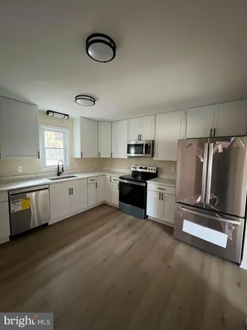 a kitchen with granite countertop a refrigerator oven a sink dishwasher and white cabinets next to a window