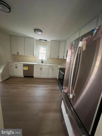 a kitchen with a refrigerator and white cabinets