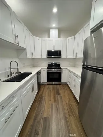 a kitchen with granite countertop a refrigerator sink and white cabinets
