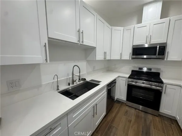 a kitchen with stainless steel appliances a sink a stove a microwave and cabinets