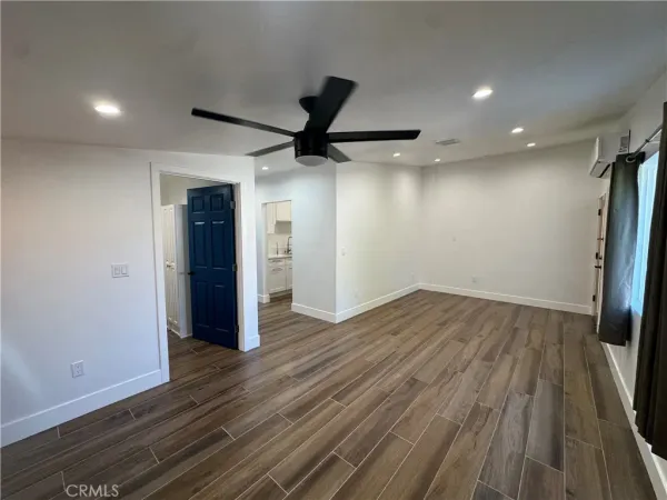 an empty room with wooden floor and a ceiling fan