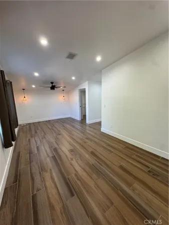 an empty room with wooden floor and a sink