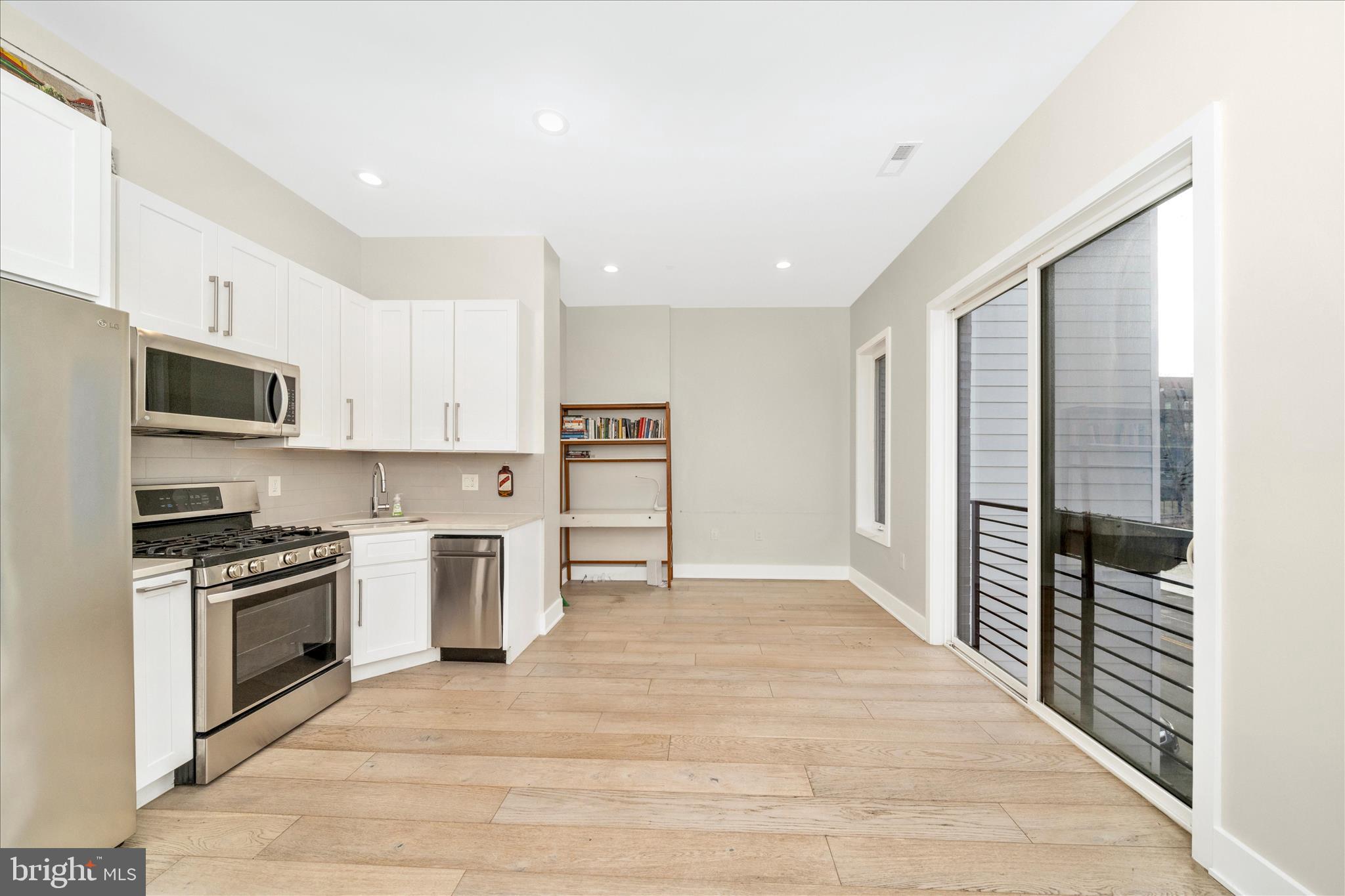 7129 Georgia Avenue Northwest, Unit 4 Washington, DC 20012 - Photo 12 of 30 a kitchen with stainless steel appliances a stove top oven a refrigerator white cabinets and wooden floor