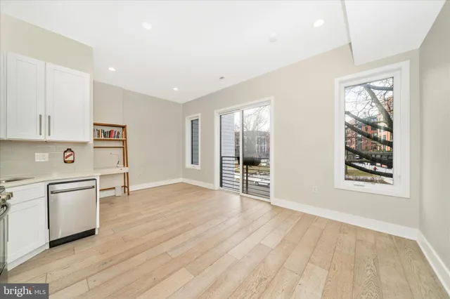 a kitchen with stainless steel appliances a stove top oven a refrigerator white cabinets and wooden floor