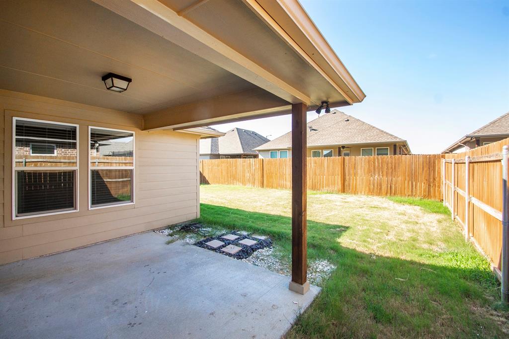 806 Ransom Way Greenville, TX 75402 - Photo 22 of 27 Covered concrete patio with an outdoor light fixture, wood support column, and a fully fenced backyard featuring a grassy area