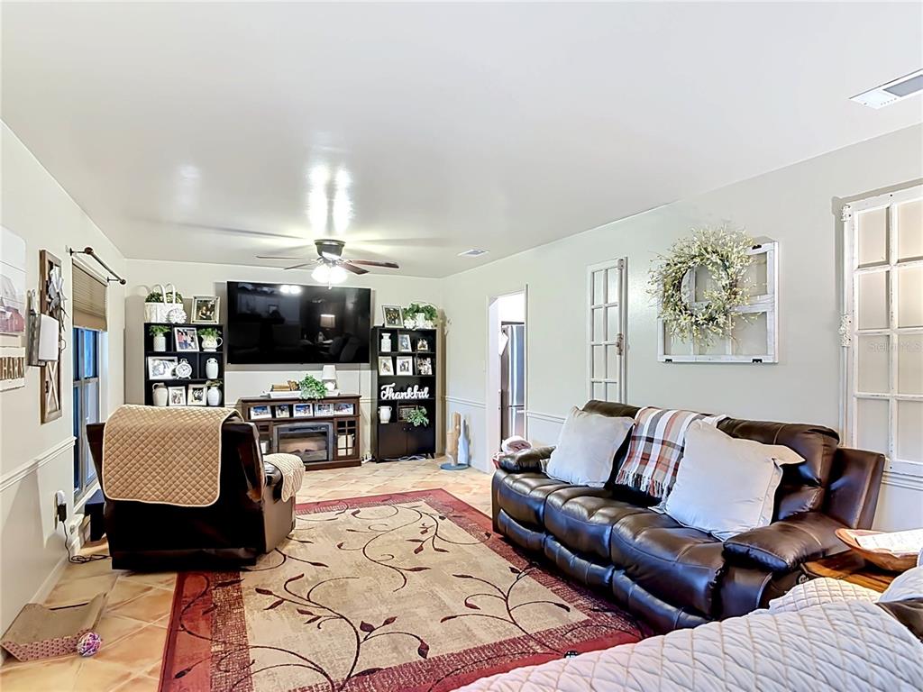 1395 Maytown Road Osteen, FL 32764 - Photo 12 of 65 a living room with furniture a flat screen tv and kitchen view
