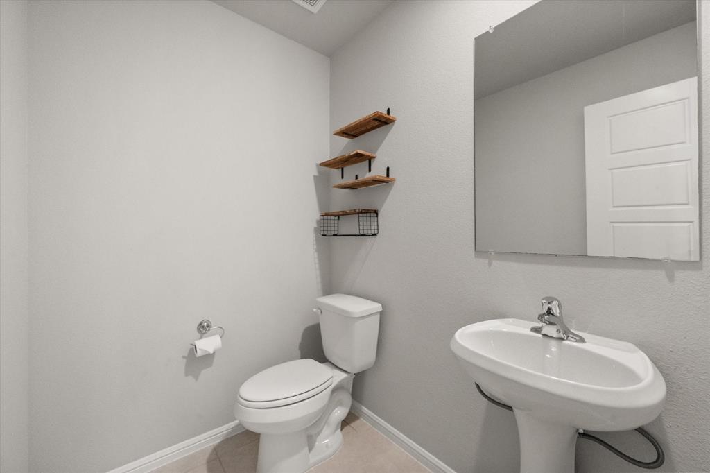 6910 Prairieside Trail Venus, TX 76084 - Photo 29 of 40 Well-appointed powder room featuring a pedestal sink and decorative wall shelving is just off the game room.