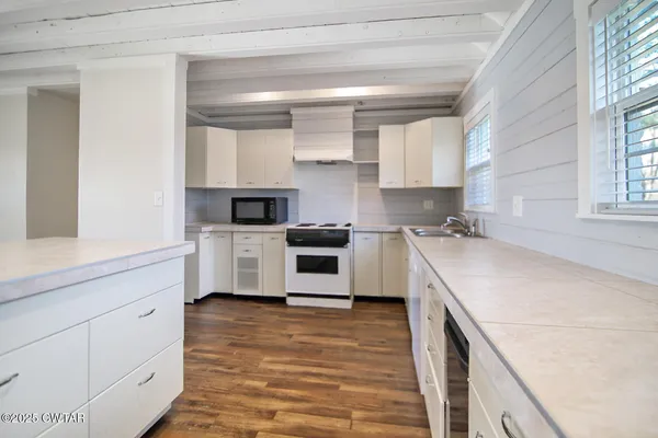 a kitchen with stainless steel appliances kitchen island granite countertop a stove a sink and white cabinets