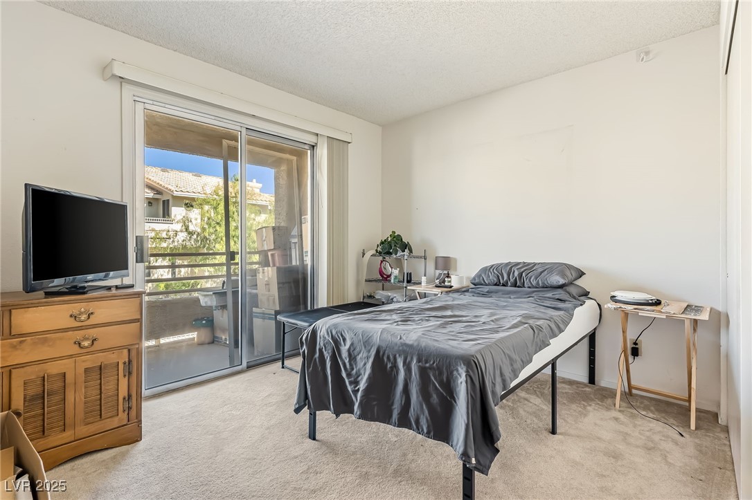 2180 Highpointe Drive, Unit 203 Laughlin, NV 89029 - Photo 13 of 20 Bedroom with light carpet, access to outside, and a textured ceiling