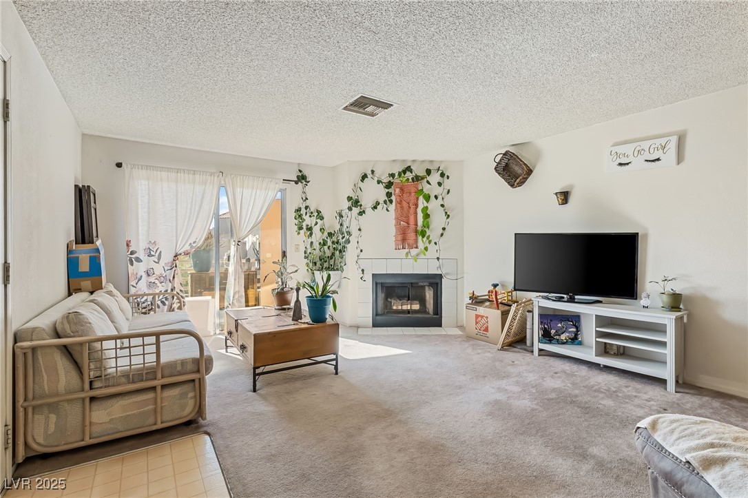 2180 Highpointe Drive, Unit 203 Laughlin, NV 89029 - Photo 3 of 20 Carpeted living area with a tiled fireplace and a textured ceiling
