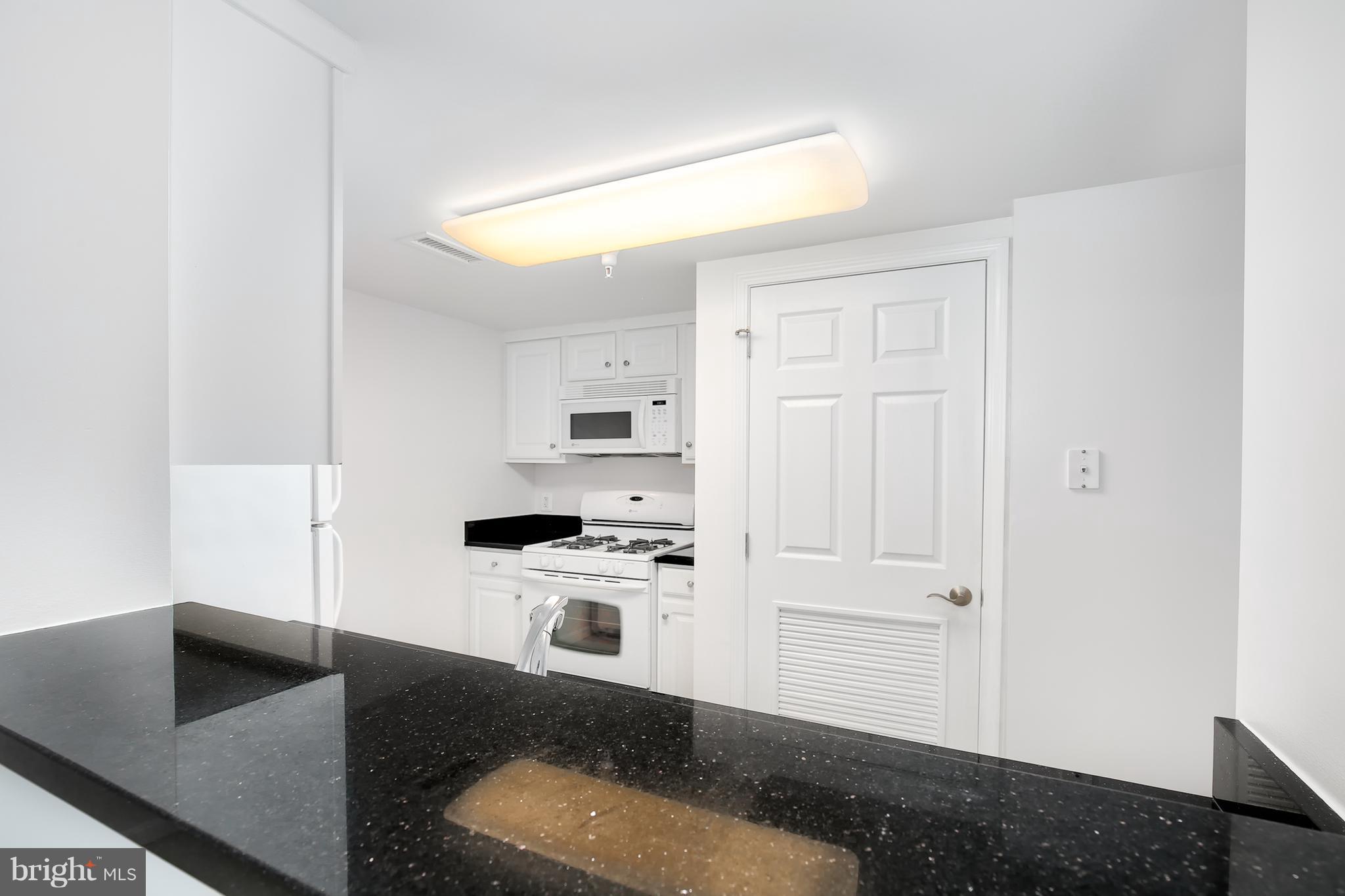 11710 Old Georgetown Road, Unit 1124 North Bethesda, MD 20852 - Photo 7 of 30 a kitchen with stainless steel appliances granite countertop a sink and a stove with white countertops