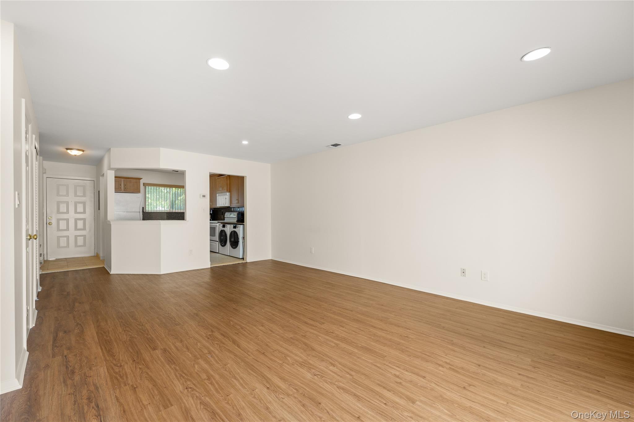 650 Newbridge Road, Unit 15 East Meadow, NY 11554 - Photo 6 of 20 a view of a big room with wooden floor and a kitchen