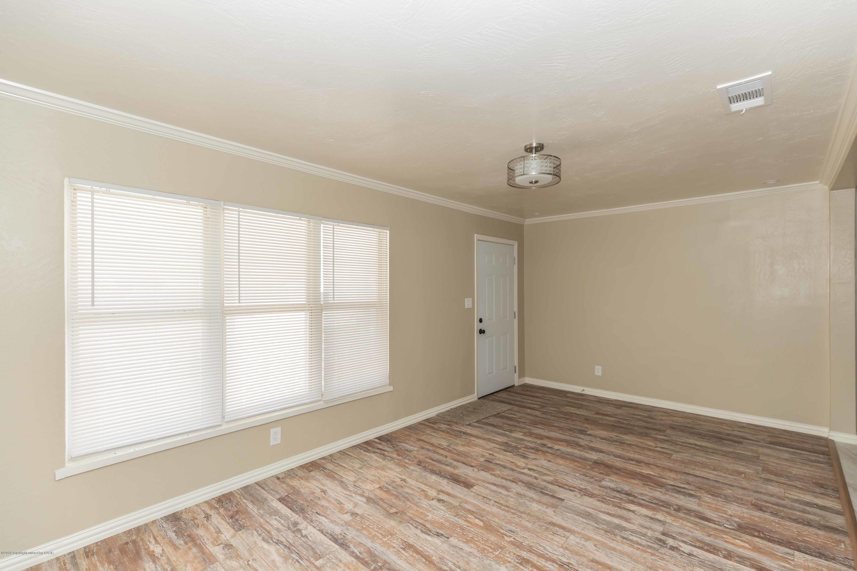 1410 Southwest 46th Avenue Amarillo, TX 79110 - Photo 3 of 29 an empty room with wooden floor and windows
