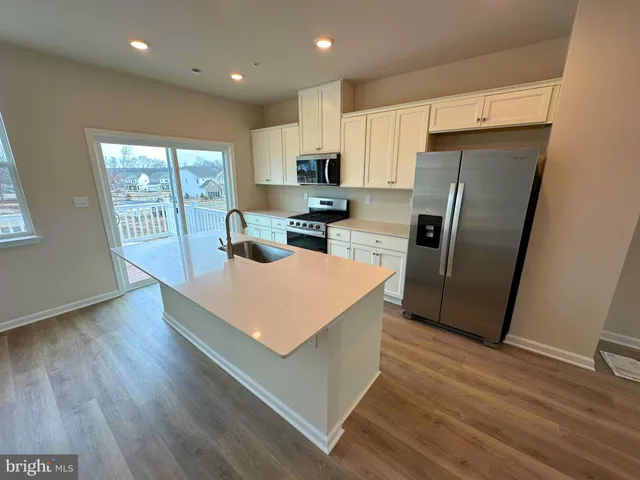 a kitchen with stainless steel appliances a refrigerator a sink a stove a microwave and island