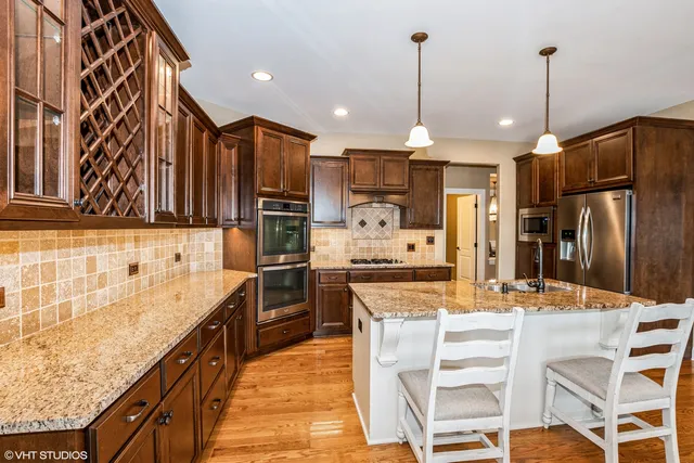 a kitchen with stainless steel appliances kitchen island granite countertop a sink refrigerator and cabinets